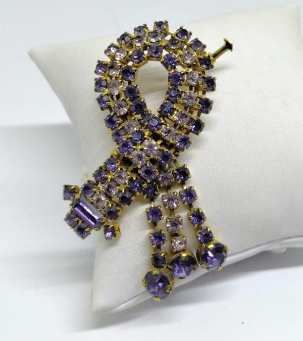 Broche avec pavage de strass violet et pampilles.