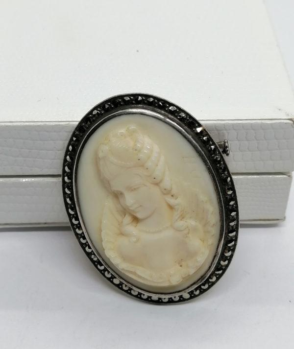 Broche, argent avec marcasites et camée en bakélite blanche.