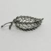 Broche argent , feuille galbée et sertie de pierres blanche.