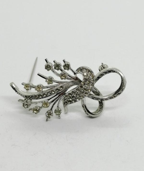 Broche argent, façon florale et ruban, sertie de strass blanc.