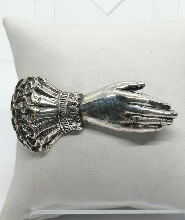 Broche en métal blanc représentant une main.
