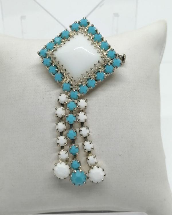 Broche de couleur bleu turquoise et blanc avec pampilles.
