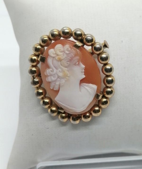 Broche métal plaqué or avec camée coquillage.