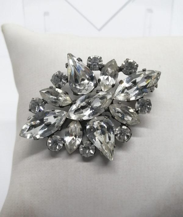 Broche en métal, ajourée et pavage de strass blanc avec navettes.
