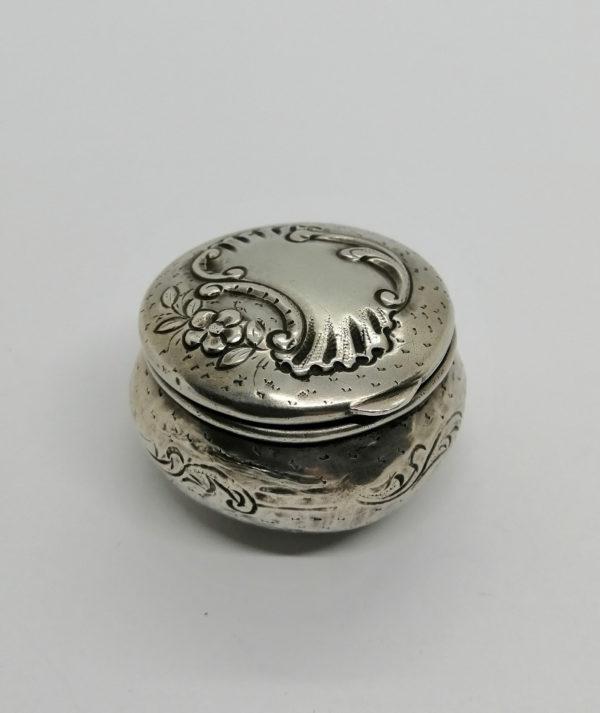 Boîte à pilules argent, décor coquille et fleur, sur fond guilloché et martelé,1900.