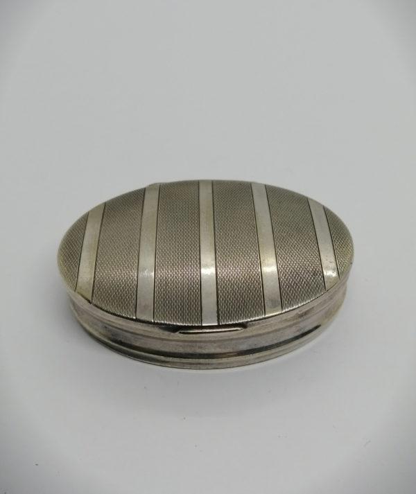 Boîte à pilules en argent, de forme ovale, couvercle guilloché, 1900-30.