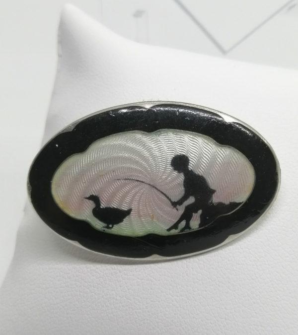 Broche argent, de forme ovale et décor sur fond guilloché émaillé.
