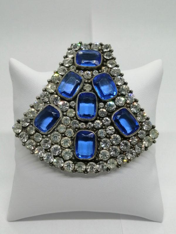 Grande broche façon clip de col, avec strass blanc et pierre bleu à facettes.