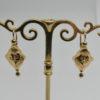 Paire de boucles d'oreilles en or jaune, demi-pendante avec motif stylisé, fin 19ième siècle. – Image 3