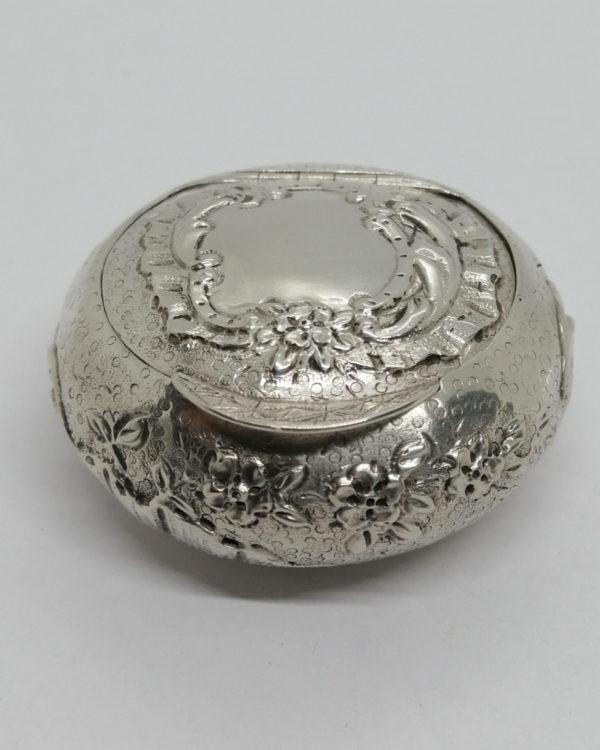 Boîte à pilules en argent massif, fond travaillé, avec fleurs et coquilles, vers 1900.