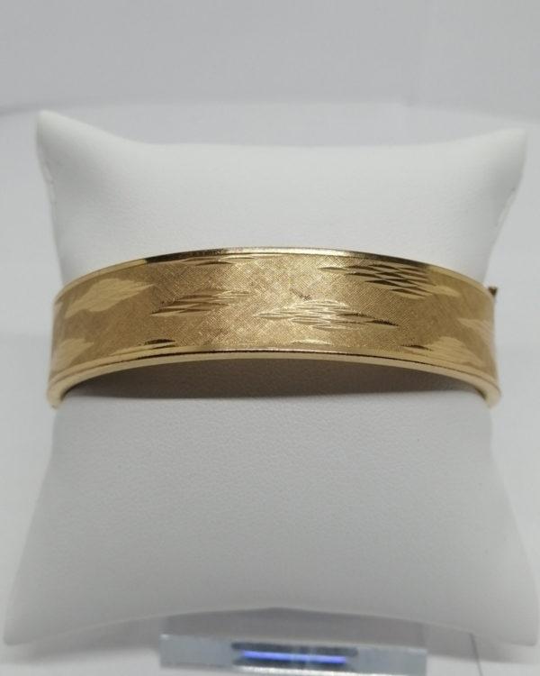 Bracelet, jonc plaqué or, sur fond brossé et guilloché des motifs à facettes, 1940-50.