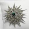 Broche métal blanc, forme étoile et pavage de strass blanc, au centre couleur émeraude, 1930-40.