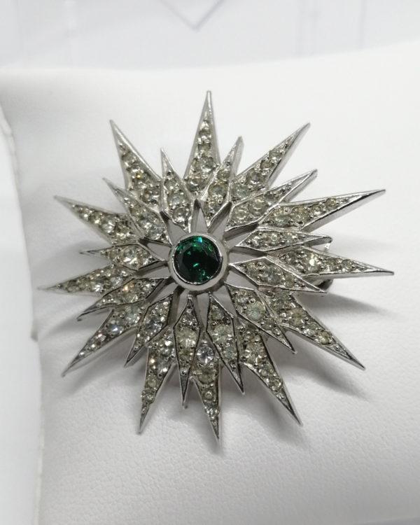 Broche métal blanc, forme étoile et pavage de strass blanc, au centre couleur émeraude, 1930-40.
