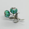 Broche argent, avec fleurs en émail, feuillages et pierres blanches.