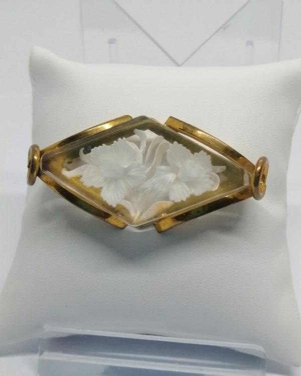 Broche, laiton jaune et plexis transparent et creusé, avec motif de fleurs, vers 1920-30.