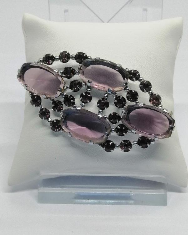 Broche, ovale, strass et pierre en pâte de verre, de couleur violet, vers 1920.